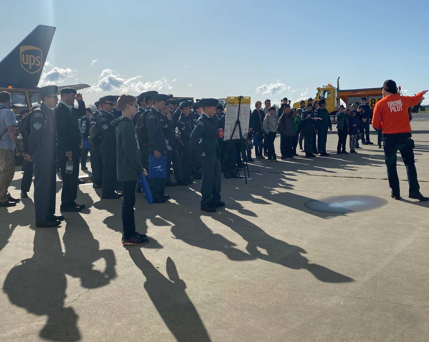 Professional drone pilot instructor conducting training session with aviation personnel on tarmac